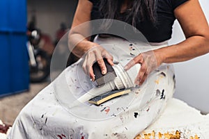 Woman filing by hand a polystyrene sculpture in a garden photo