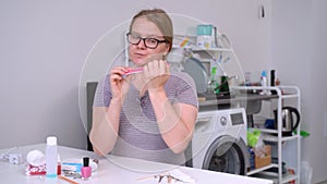 Woman filing her fingernails occasionally looking away.