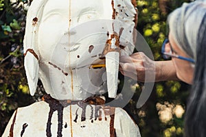 Woman filing a piece of polystyrene with a spatula outdoors photo