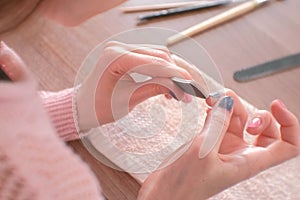 Woman filings nails nail file. Close-up hands. Tools on the table.