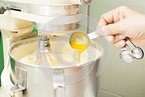 Woman fill egg and ingredient in dough mixer machine kneading.