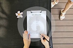 Woman fill visa application in travel agency. close up hands, pe