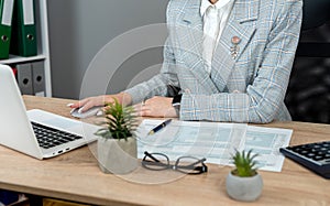 Woman filling 1040 tax forms with laptop pen and calculator at office