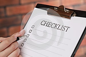 Woman filling Checklist with pen, closeup view