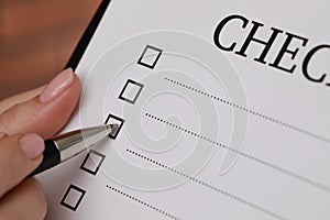 Woman filling Checklist with pen, closeup view