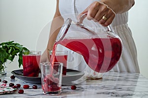 Woman is filling cranberry juice in glass.