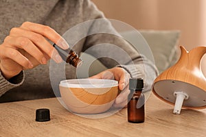 Woman filling essential oil diffuser, closeup