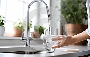 Woman filling glass with tap water from faucet in kitchen