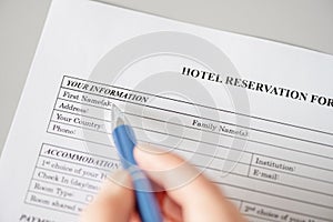 Woman filling hotel reservation form putting first name. Reception desk. Hotel service, registration. Close up. Selective focus.
