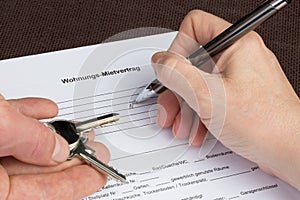 A woman is filling out a german tenancy agreement with keys in h photo
