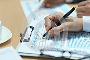 Woman filling in U.S. Individual income tax return, tax 1040 at table.