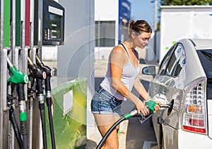 Woman filling up tank of her car with gasoline