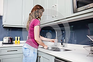 Woman filling water in glass from faucet