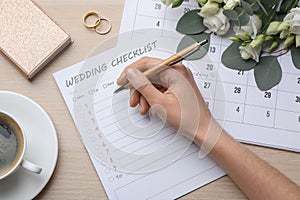 Woman filling Wedding Checklist at wooden table, top view
