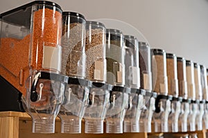 A woman fills a jar with red lentils. Selling bulk goods by weight in an eco store. Trade concept without plastic