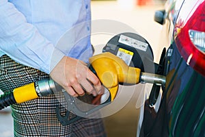 Woman fills petrol into the car at a gas station