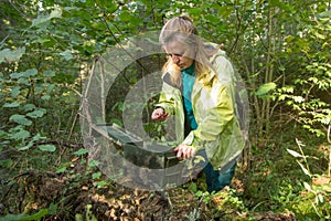 A woman finds geocaching container.