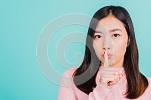 Woman with finger in front of mouth on lips