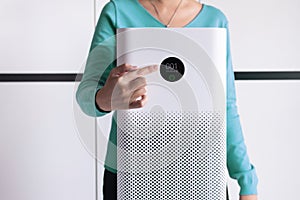 Woman finger pointing to screen of white modern air purifier in a living room for refresh air flow at home,Advanced air purifying