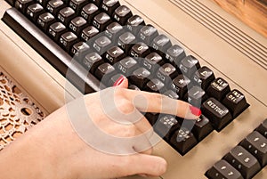 Woman finger press button on old computer keyboard