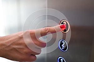 Woman finger presses a button in elevator closeup