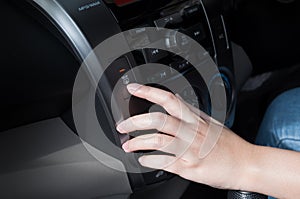 Woman finger pressing button defrost detail on a car`s dashboard