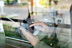 woman finger touching on digital tablet see through glass in coffee shop