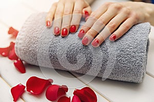 woman fingernails with red nail polish on towel roll