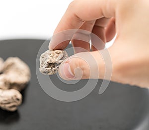 Woman fingers holding Dried salted Chinese plum seed from black