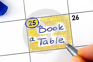 Woman fingers with pen writing reminder Book a Table in calendar