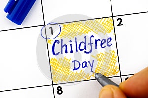 Woman fingers with pen writing reminder Childfree Day in calendar photo