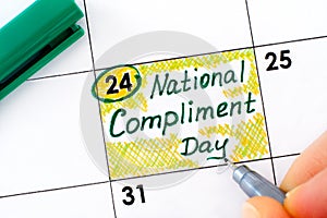 Woman fingers with pen writing reminder National Compliment Day in calendar