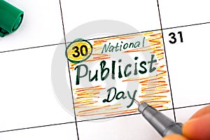 Woman fingers with pen writing reminder National Publicist Day in calendar