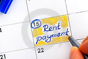Woman fingers with pen writing reminder Rent Payment in calendar