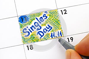 Woman fingers with pen writing reminder Singles Day 11.11 in cal