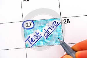 Woman fingers with pen writing reminder Test Drive in calendar