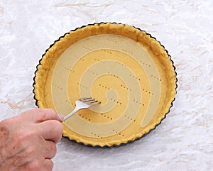 Woman finishes pricking holes in a pastry pie crust photo