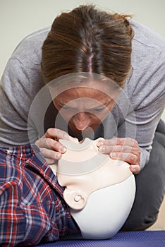 Woman In First Aid Class Performing Mouth To Mouth Resuscitation