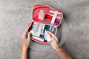 Woman with first aid kit on gray background