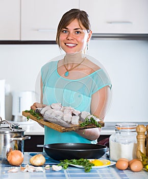 Woman with fish and frying pan at kitchen