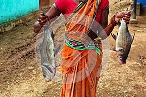 Woman fisherman with freshly harvested fish in hand