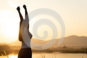 Woman with fist in the air during sunset sunrise mountain in background. Stand strong. Feeling motivated, freedom, strength and