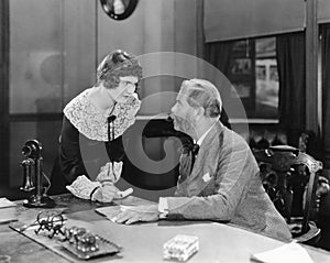 Woman with fist clenched in an office glaring at her boss