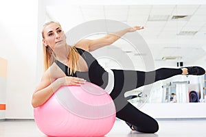 Woman on fitball doing side bend exercise workout at gym indoor