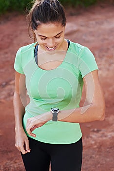 Woman, fitness and check smart watch in nature for workout goals, running and cardio results. Sports person or runner