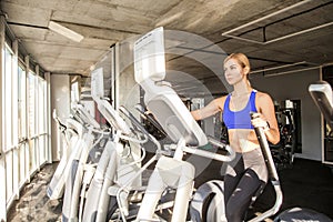 Woman in fitness club or gym, ride on orbitrack photo