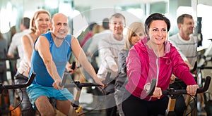 Woman on fitness cycle with people