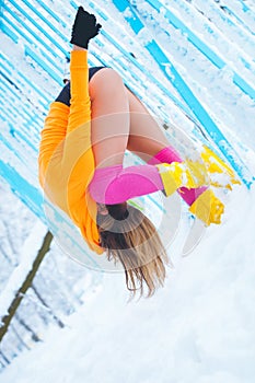 Woman fitness instructor workout outdoor in snow by the metal fence winter