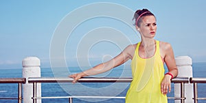 Woman in fitness outfit looking aside and listening to music