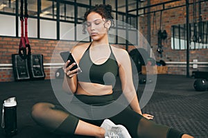 Woman, fitness and phone at gym for a workout, training and body wellness with a mobile app. Young sports female with